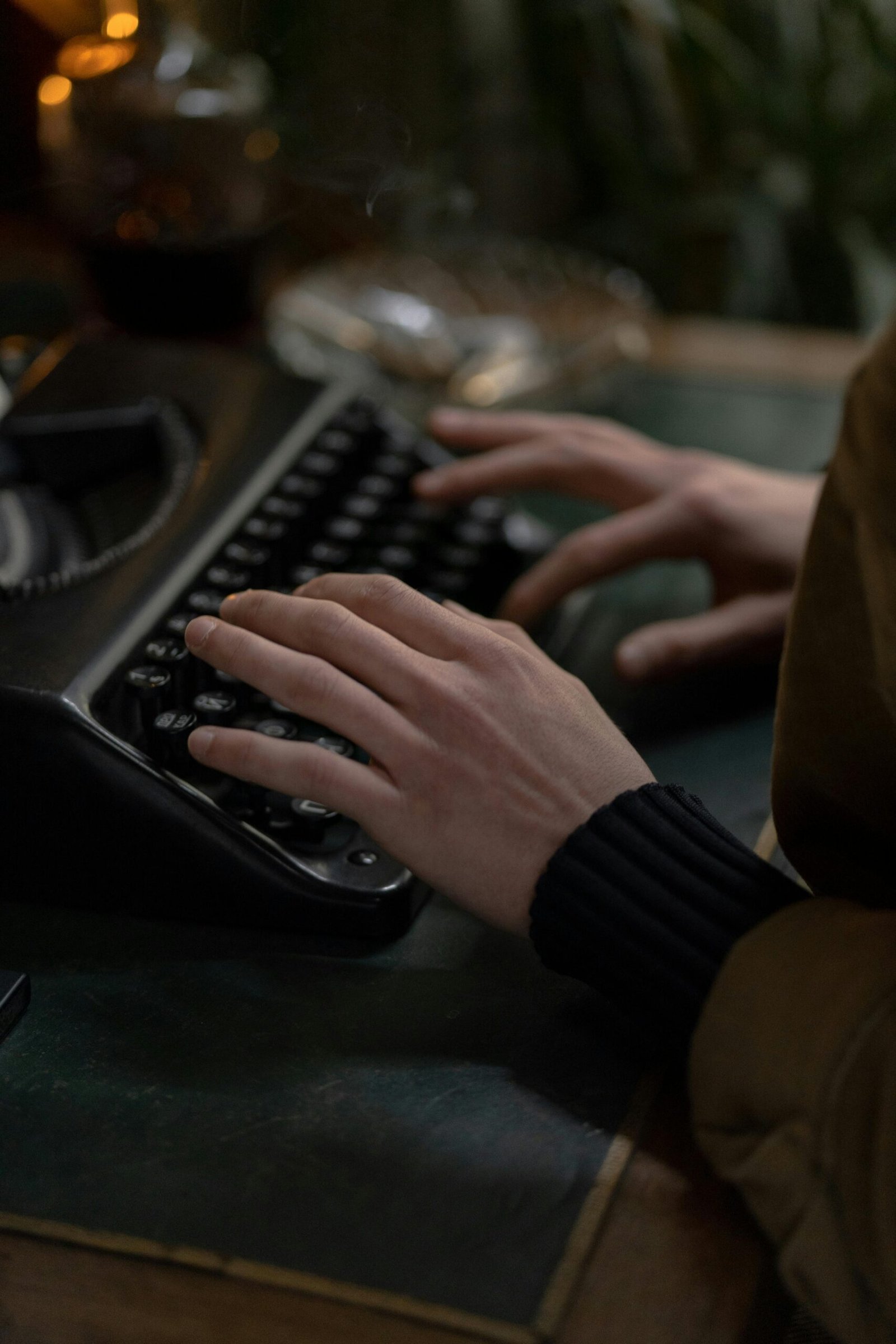 pexels-photo-6037575-6037575 Hands of an adult typing on a vintage typewriter, set indoors with classic tones.
