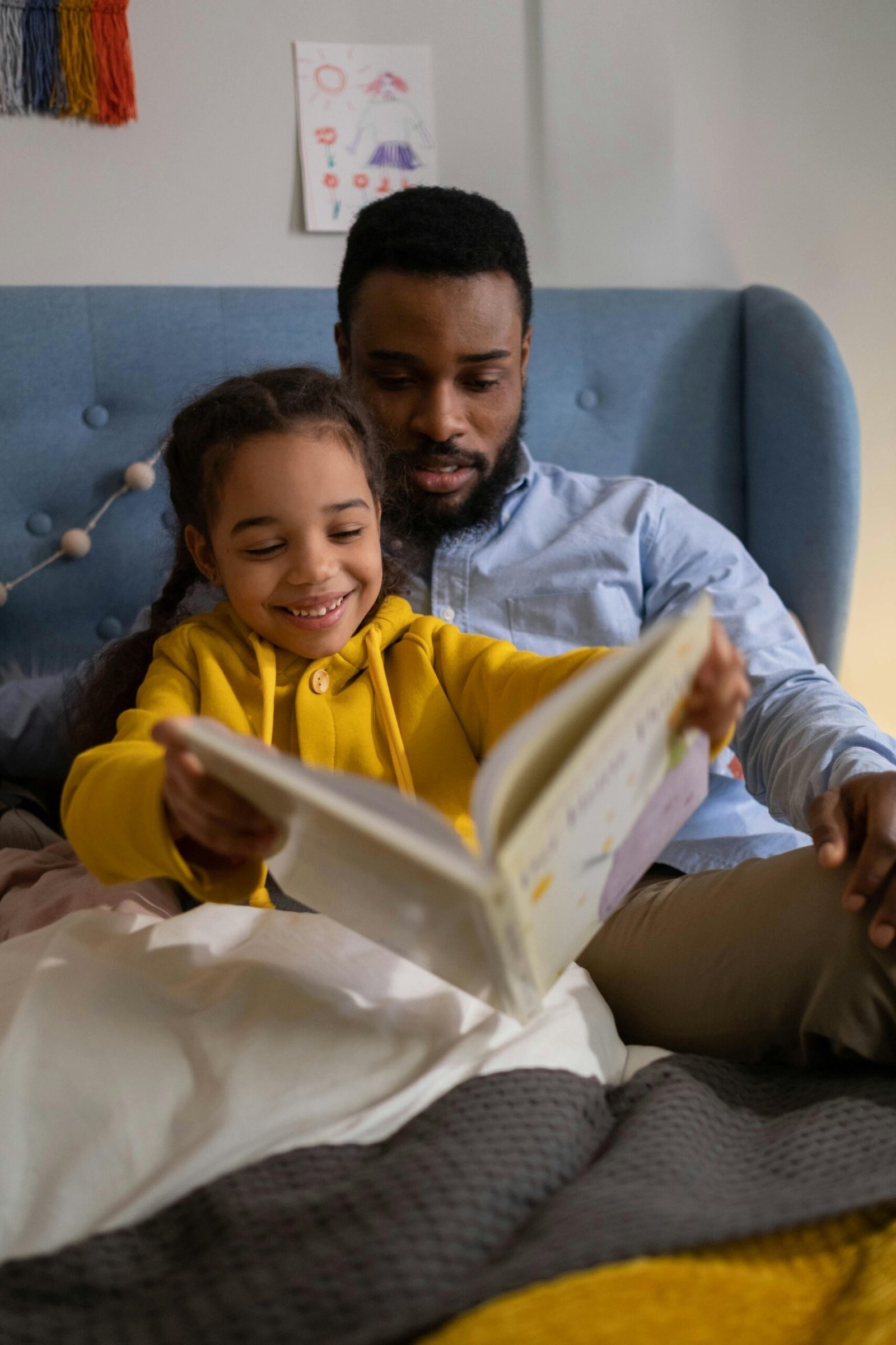 A joyful moment of a father and daughter reading together in a cozy bedroom setting.