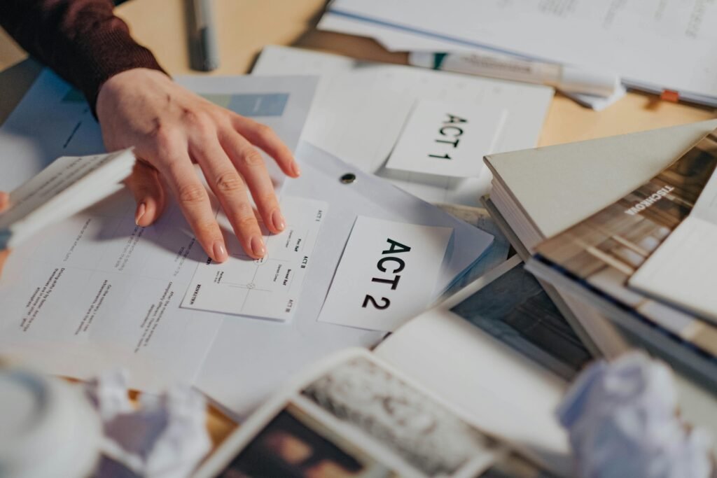 pexels-photo-8086362-8086362 A cluttered desk with scripts, notes, and a person's hand organizing screenplay drafts.